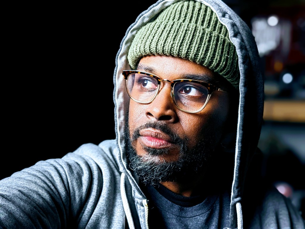 
Portrait of Mike wearing a green knit cap and a gray hooded sweatshirt.